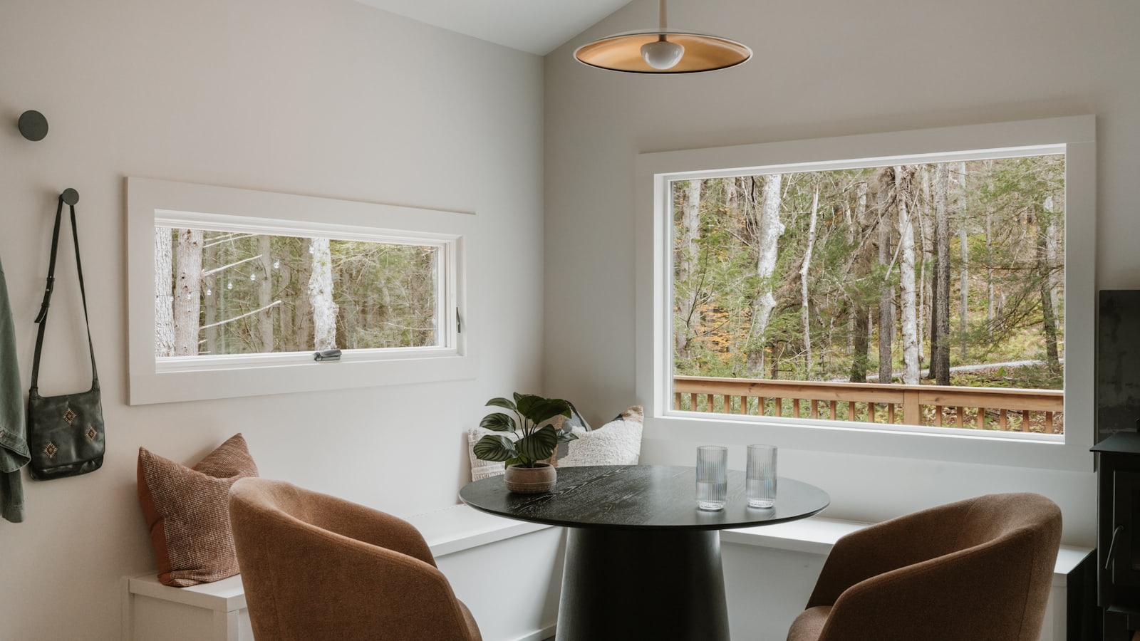 A cottage dining nook with a window seat looking out into the trees.