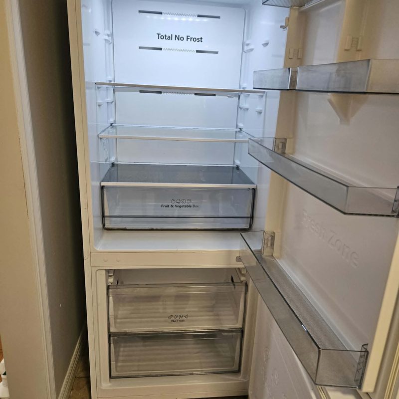 The same fridge after cleaning, shelves and drawers clear and wiped through.