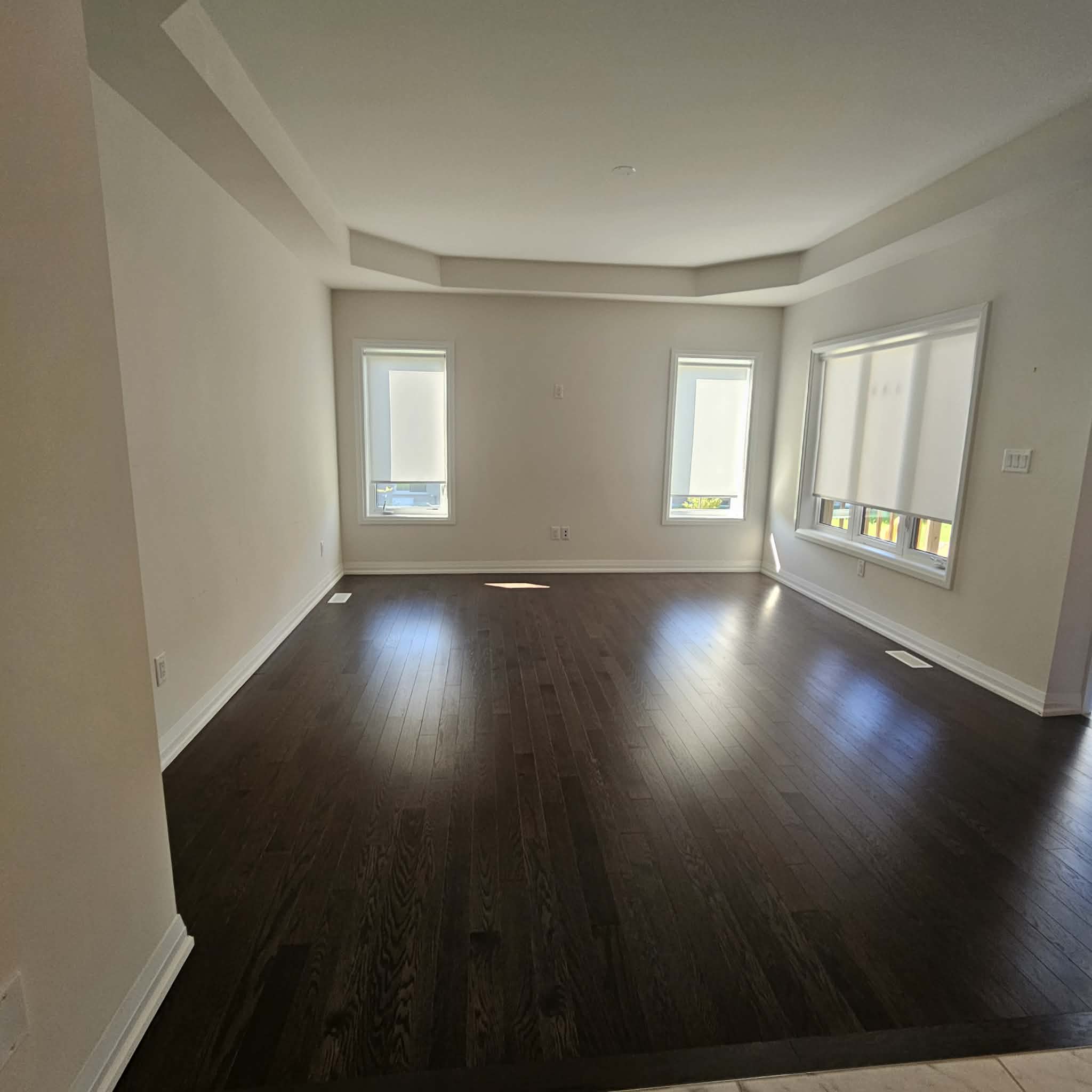 An empty living room with dark hardwood floors, cleaned and ready for the next owners.