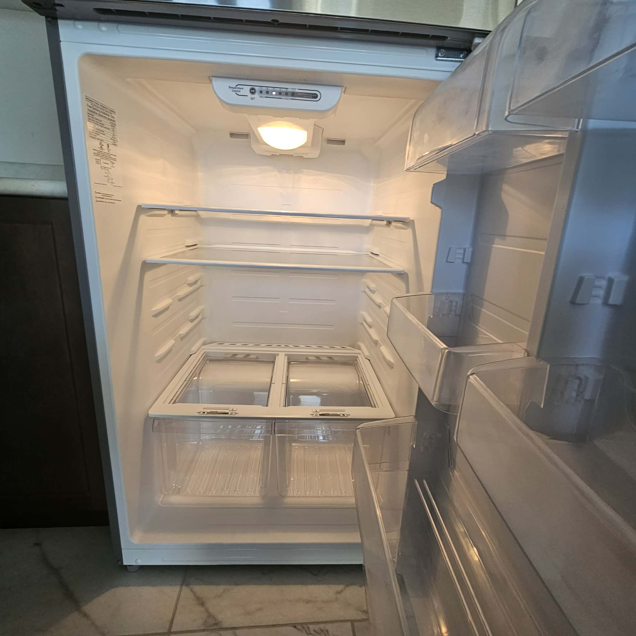 The inside of a fridge, emptied and wiped down to the shelves.
