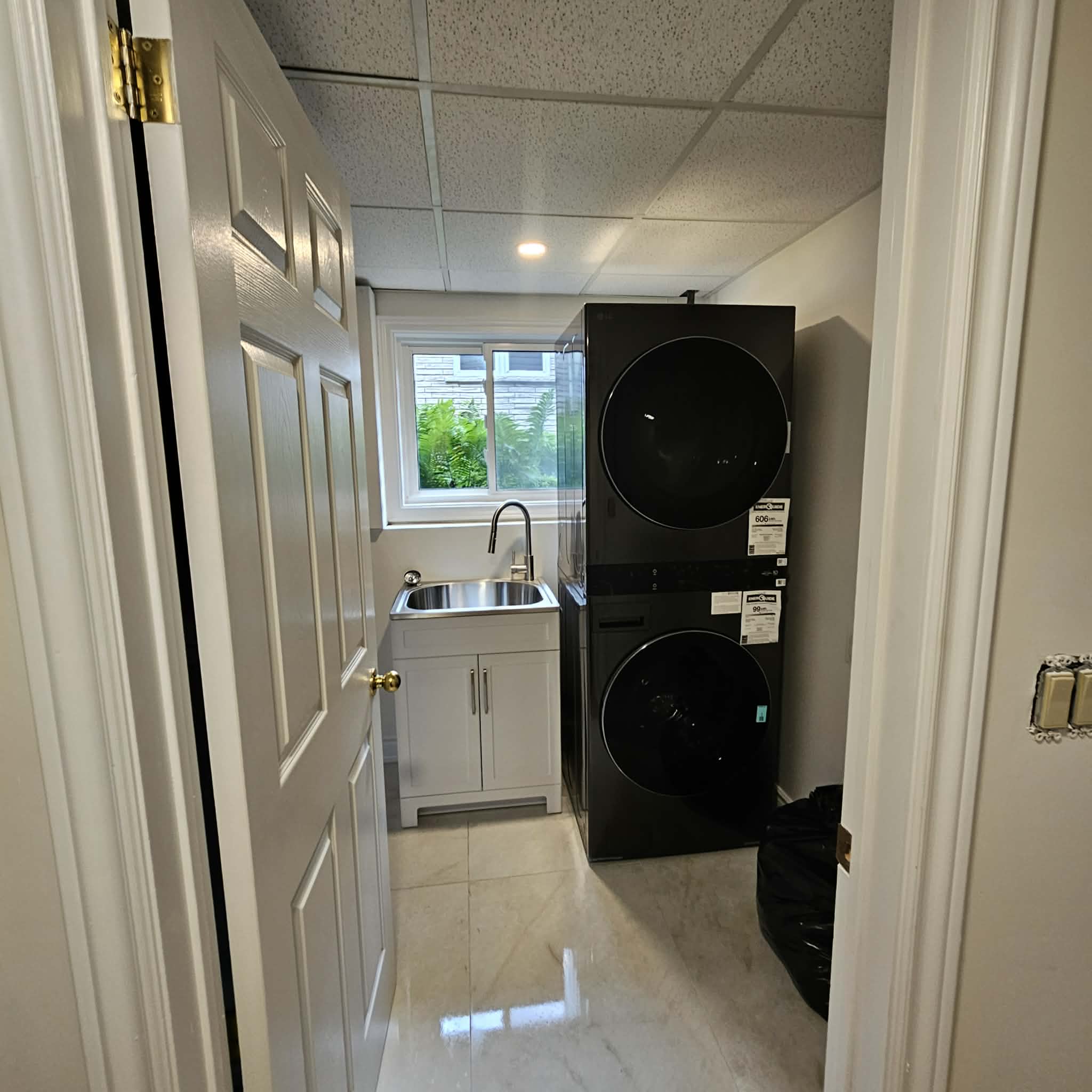 A laundry room with a stacked washer and dryer and a polished tile floor.