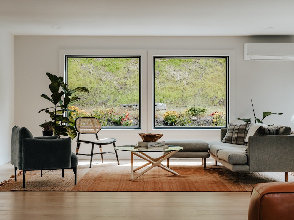 A bright living room with tall windows looking out onto a green hillside.