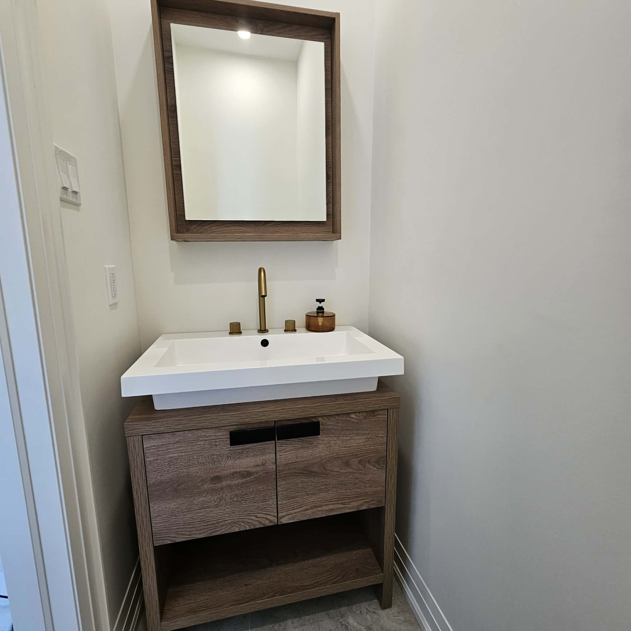 A walnut vanity with a white basin and brass tap, wiped down and finished.